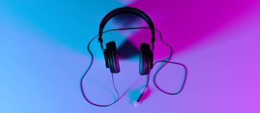 Siyah arka plandaki kulaklıklar neon ışıkta yakın plan.