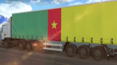 Otoyolda giden büyük bir kamyonun yanında kamerun bayrağı görülüyor.