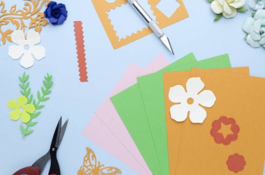 mavi bir arka plan üzerinde dağınık renkli kağıt çiçekler ve şekilleri kesim