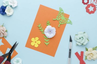 parlak mavi bir arka plan üzerinde kendi elleriyle yapılan kağıt çiçekler kartıyla