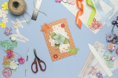 Ev yapımı tebrik kartı kağıt çiçeklerden yapılmış. Scrapbooking, yaratıcı karışıklık. Üstten Görünüm, mavi arka plan