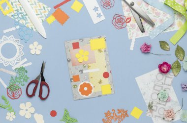 Saçak'ın renkli kağıttan ev yapımı bir kartpostal soyut. Scrapbooking, yaratıcı karışıklık. Üstten Görünüm, mavi arka plan