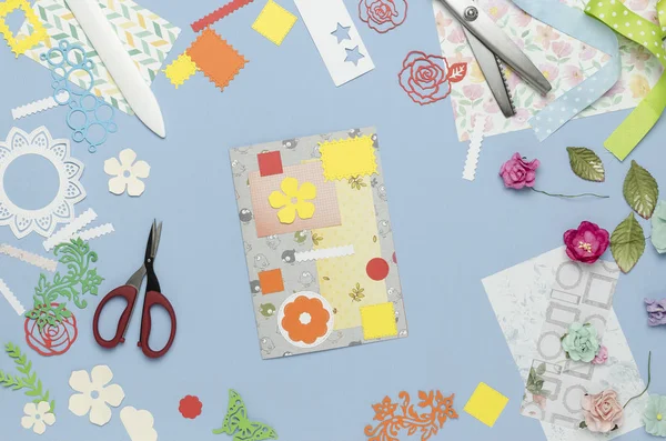 Saçak'ın renkli kağıttan ev yapımı bir kartpostal soyut. Scrapbooking, yaratıcı karışıklık. Üstten Görünüm, mavi arka plan