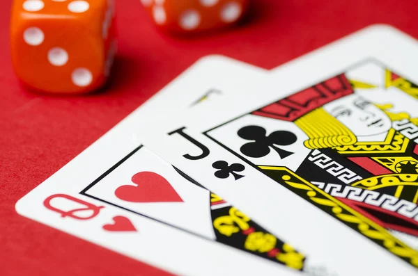 Cubes, two cards a Queen and a Jack on red background, close-up