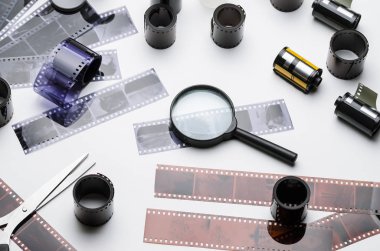 35mm film, makas ve beyaz arka plan üzerinde büyüteç