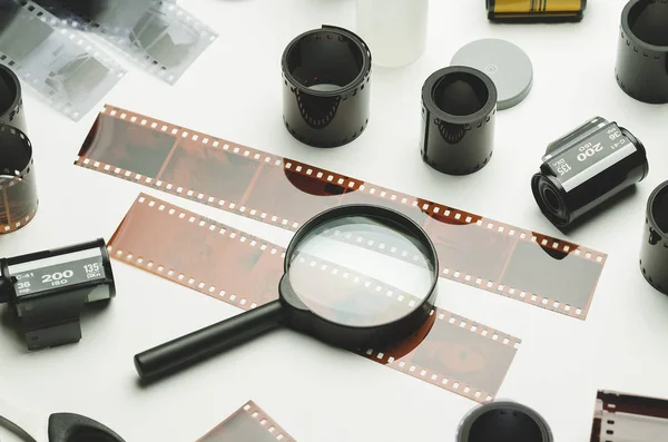 Multiple photographic films and magnifying glass on white background