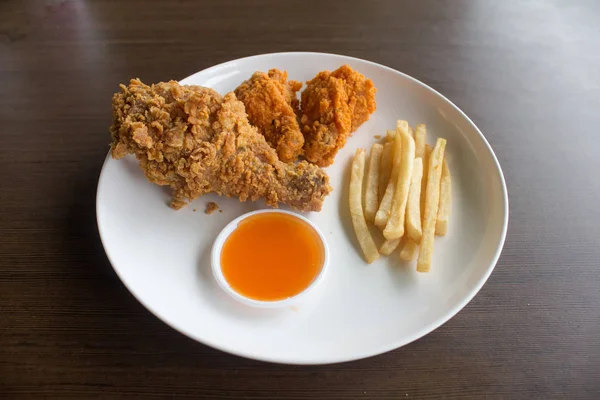 Fried chicken legs and french fries on white color plate, Fast food spicy chicken legs and chilli sauce select focus, Close-up fried chicken and french fries