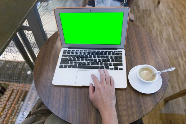Youngman working with laptop in cafe, laptop with green screen.