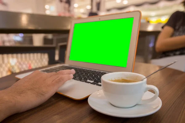 Youngman working with laptop in cafe, laptop with green screen.