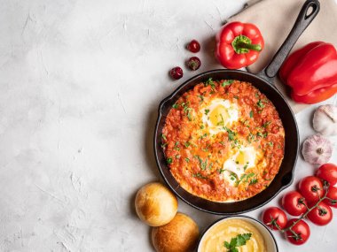 Dolmalık biberli Shakshuka, domates, humus ve rulo. Üst görünüm, metin için yer.