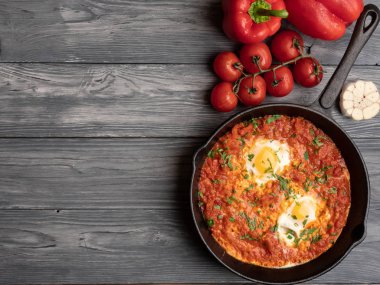 Dolmalık biberli Shakshuka, domates, humus ve rulo. Üst görünüm, metin için yer.