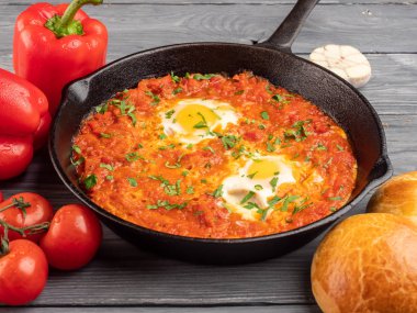 Dolmalık biberli Shakshuka, domates, humus ve rulo.