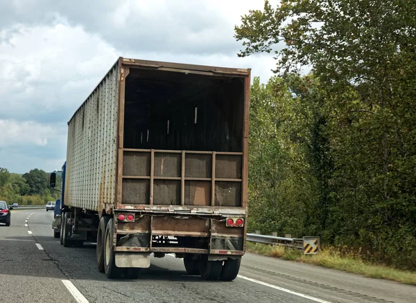 Trucking Industry: Rear view of open back semi trailer on highway under blue sky.