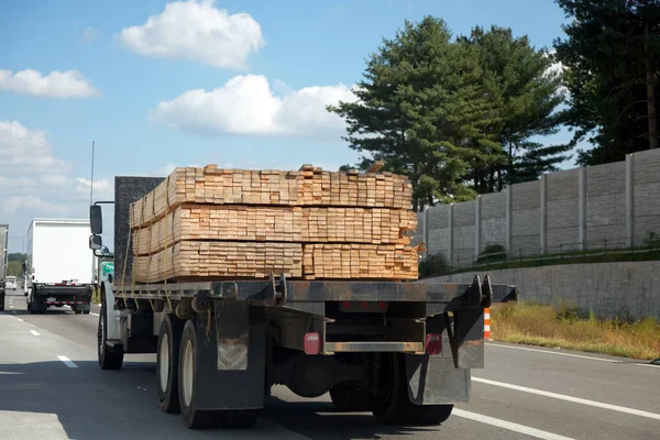 Trucking Industry: Flatbed trailer with lumber cargo.