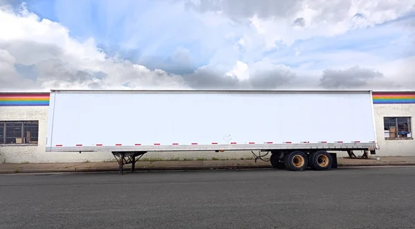 Trucking industry: Side view of semi parked white trucking trailer.