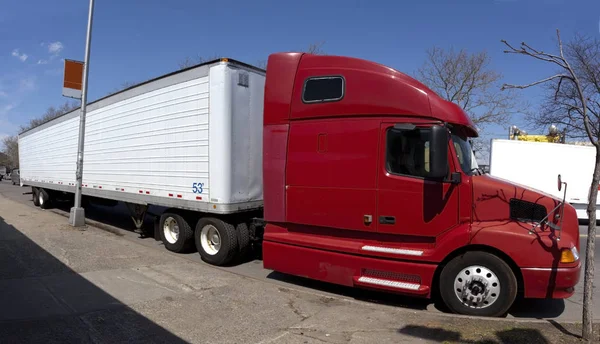 Trucking industry: side view of red semi cab and white trailer.