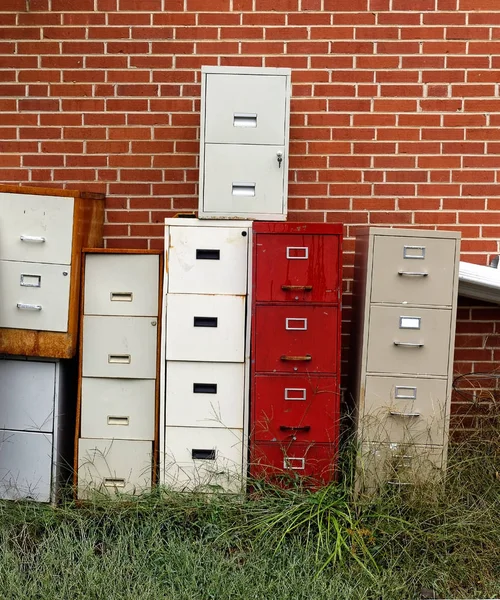 Old Filing Cabinets: Thrift store collection of file cabinets stacked against brick wall.