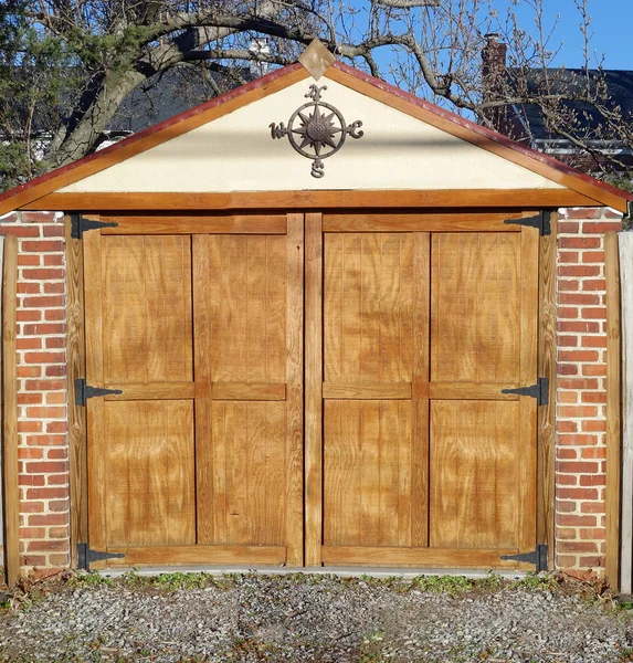 Utility Shed: Wood shed with brick columns and compass rose.