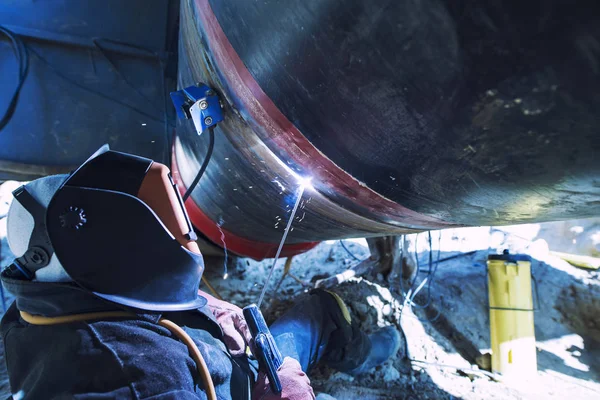 Soldador profesional tubería de soldadura en una construcción de tubería. Trabajador conectando dos tubos de metal. Soldadura industrial . —  Fotos de Stock