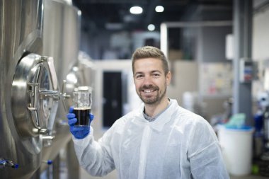 Portrait of technologist testing product quality in beverage alcohol production plant.