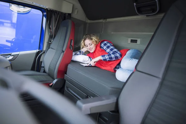 Truck driver lying on bed in his cabin communicating with his family via tablet computer. People separated from their families. Trucker lifestyle. — Stock Photo, Image