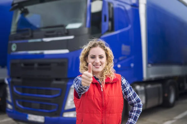 Retrato de motorista de caminhão profissional mostrando polegares para cima e sorrindo. Veículo de camião no fundo. Serviços de transporte. Profissão de camionistas . — Fotografia de Stock