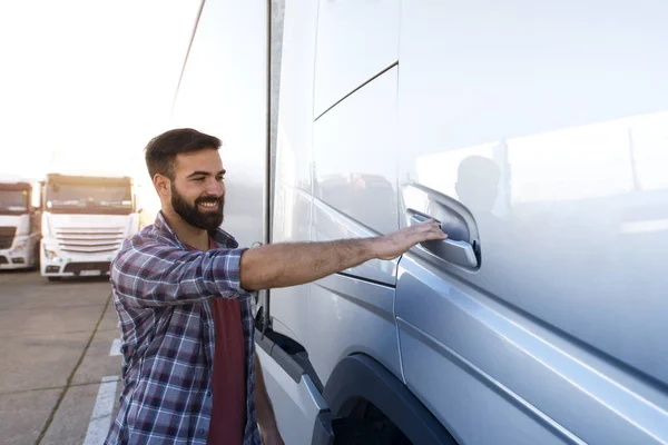 Vrachtwagenchauffeur beroep. Jonge bebaarde trucker openen vrachtwagen deur om de cabine in te gaan en te beginnen met rijden. Vervoer van goederen. — Stockfoto