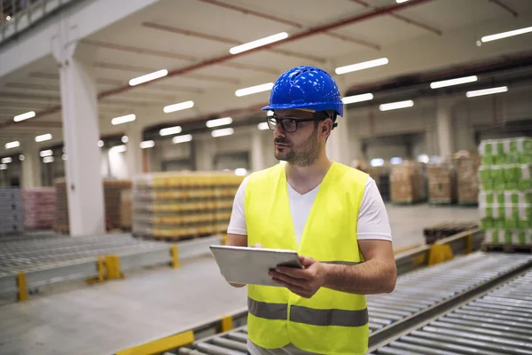 Portret van een blanke magazijnmedewerker met tablet in de opslagruimte. Mannelijke werknemer die de goederenverzending in de fabriek controleert. — Stockfoto