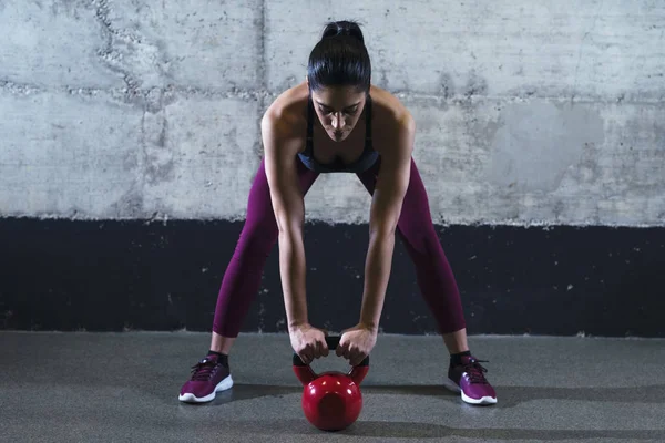 Mujer fitness en ropa deportiva haciendo ejercicio con el peso de la campana hervidor en el gimnasio. Entrenamiento y deporte . — Foto de Stock