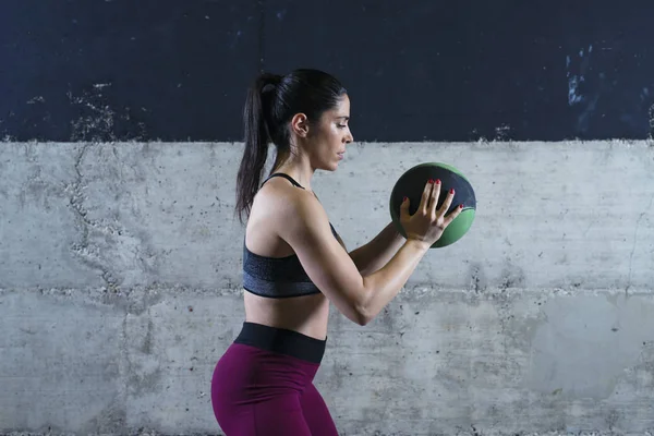 Mujer fitness sosteniendo balón de medicina y ejercitándose en el gimnasio . — Foto de Stock