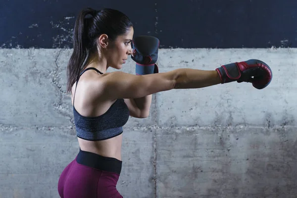 Fitness mujer musculosa con guantes de boxeo haciendo ejercicio en el gimnasio. Entrenamiento y deporte . — Foto de Stock