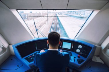 İçi tren kokpiti. Şoför oturuyor ve tren sürüyor..