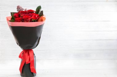 Hafif ahşap arka plan üzerinde siyah kağıt kırmızı gül