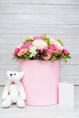 Narin buket pembe kutusunda bir beyaz ayı ve hafif ahşap arka plan üzerinde bir kart ile