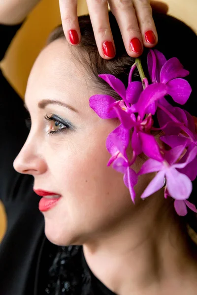 Portrait of a beautiful happy woman with an orchid in her hair