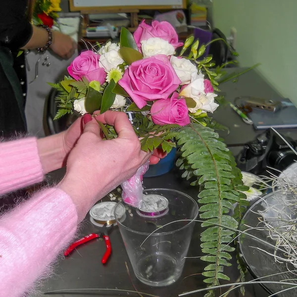 Women\'s hands make a bridal bouquet of roses