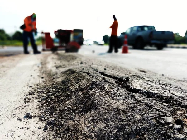 Asfalt yol hasar görmüş. Ve yolu tamir eden işçiler var. — Stok fotoğraf