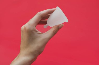 Pembe arka planda regl fincanı. Alternatif kadın hijyen ürünü