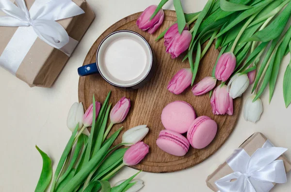 Coffee cup, spring tulip flowers and pink macarons on wooden table top view. Greeting for Womans or Mothers Day 로열티 프리 스톡 사진