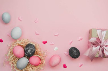 Paskalya yumurtaları ve renkli yumurtalar ve pembe arka planda kalpler.