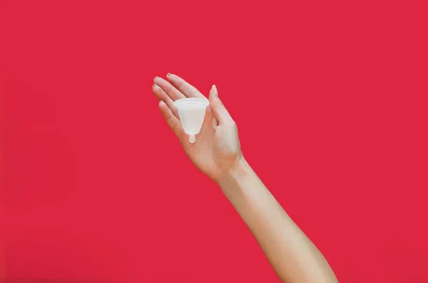 Menstrual cup in hand on red background. Alternative feminine hygiene product — Stockfoto