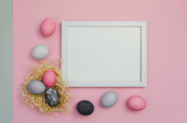 Pembe ve gri arkaplanlı renkli Paskalya yumurtaları ve metin için çerçeve
