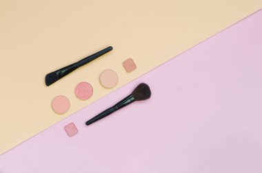 Pembe ve sarı arka planda renkli kozmetik ürünler var. Düz Yatay