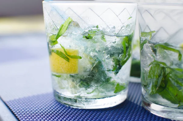 Full glass of fresh cool transparent water with ice, lemon and , basil leaves — Stock Photo, Image