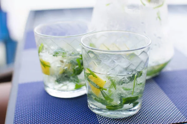 Two full glasses of fresh cool transparent water with ice, lemon and , basil leaves — Stock Photo, Image