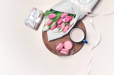 Kahve fincanı, bahar lale çiçekleri ve pastel masadaki pembe badem kurabiyeleri. Üst Manzara. Kadınlar ve Anneler Günü 'nü kutluyoruz. Düz yatıyordu.