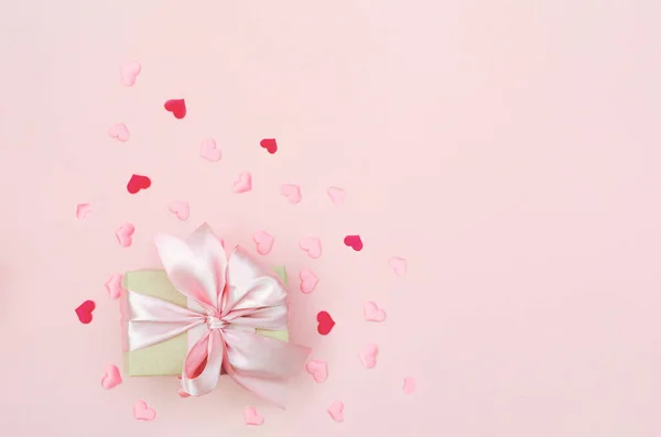 Presentera med rosa rosett på rosa bakgrund med titel hjärtan. Platt låg trendig stil. — Stockfoto