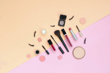 Pembe ve sarı arka planda renkli kozmetik ürünler var. Düz Yatay