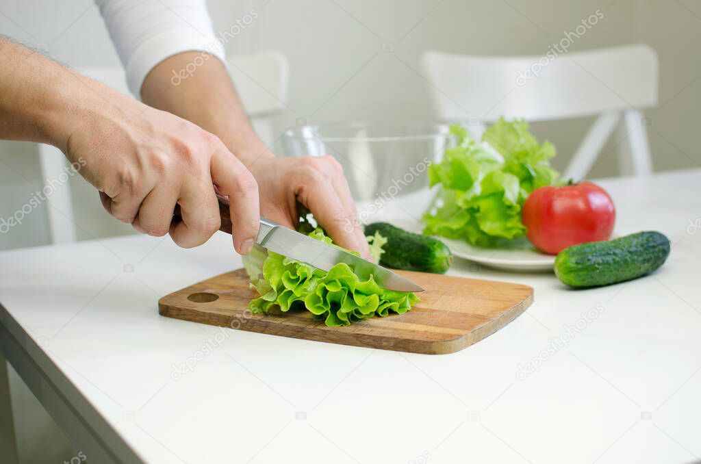 Male hands prepairing salad. Cutting salat.