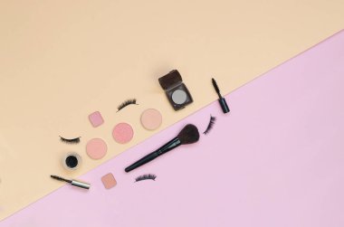 Pembe ve sarı arka planda renkli kozmetik ürünler var. Makyaj hazır. Tasarım için düz arkaplan